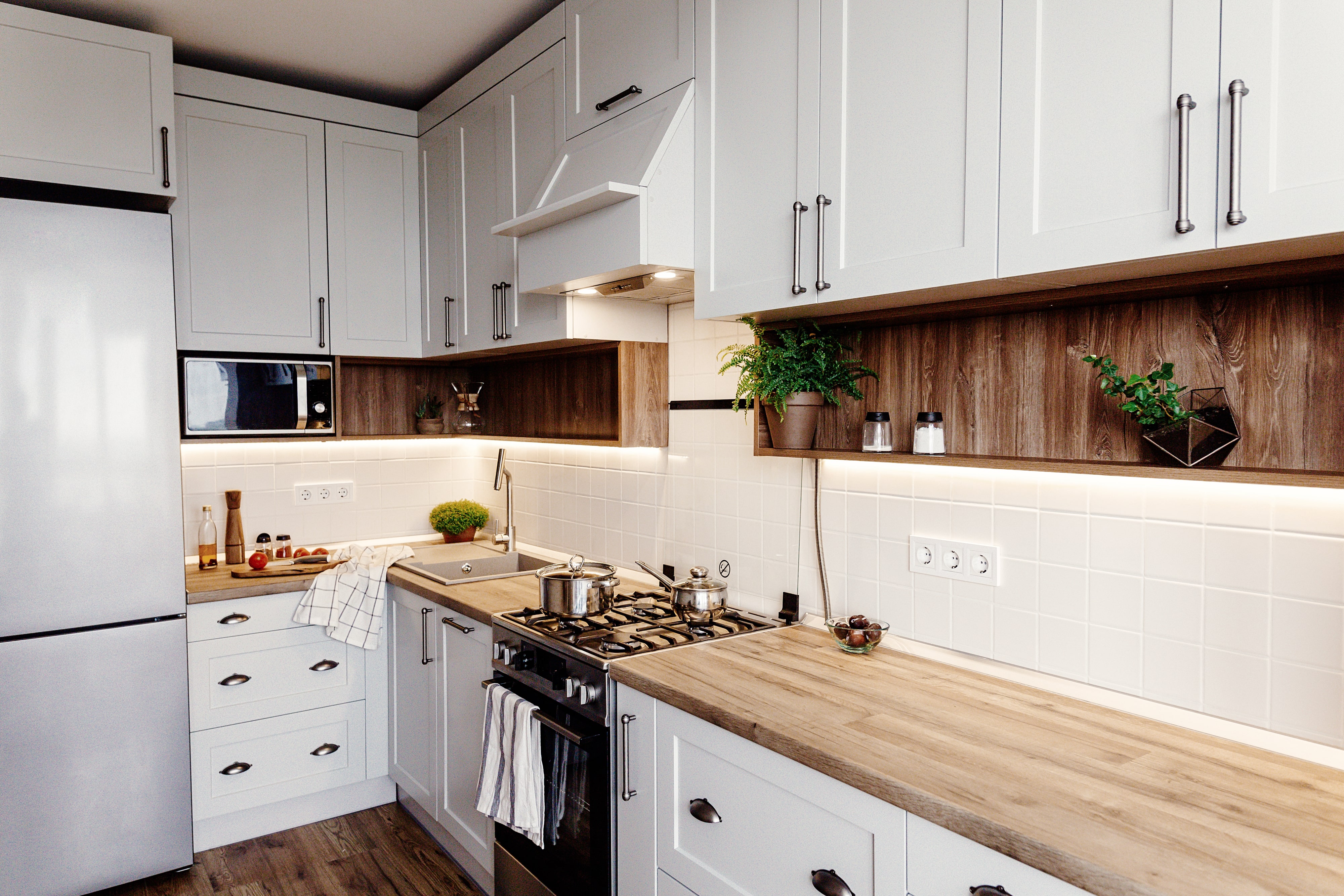 A kitchen with white cabinets, wooden shelving, wood countertops, and wood flooring