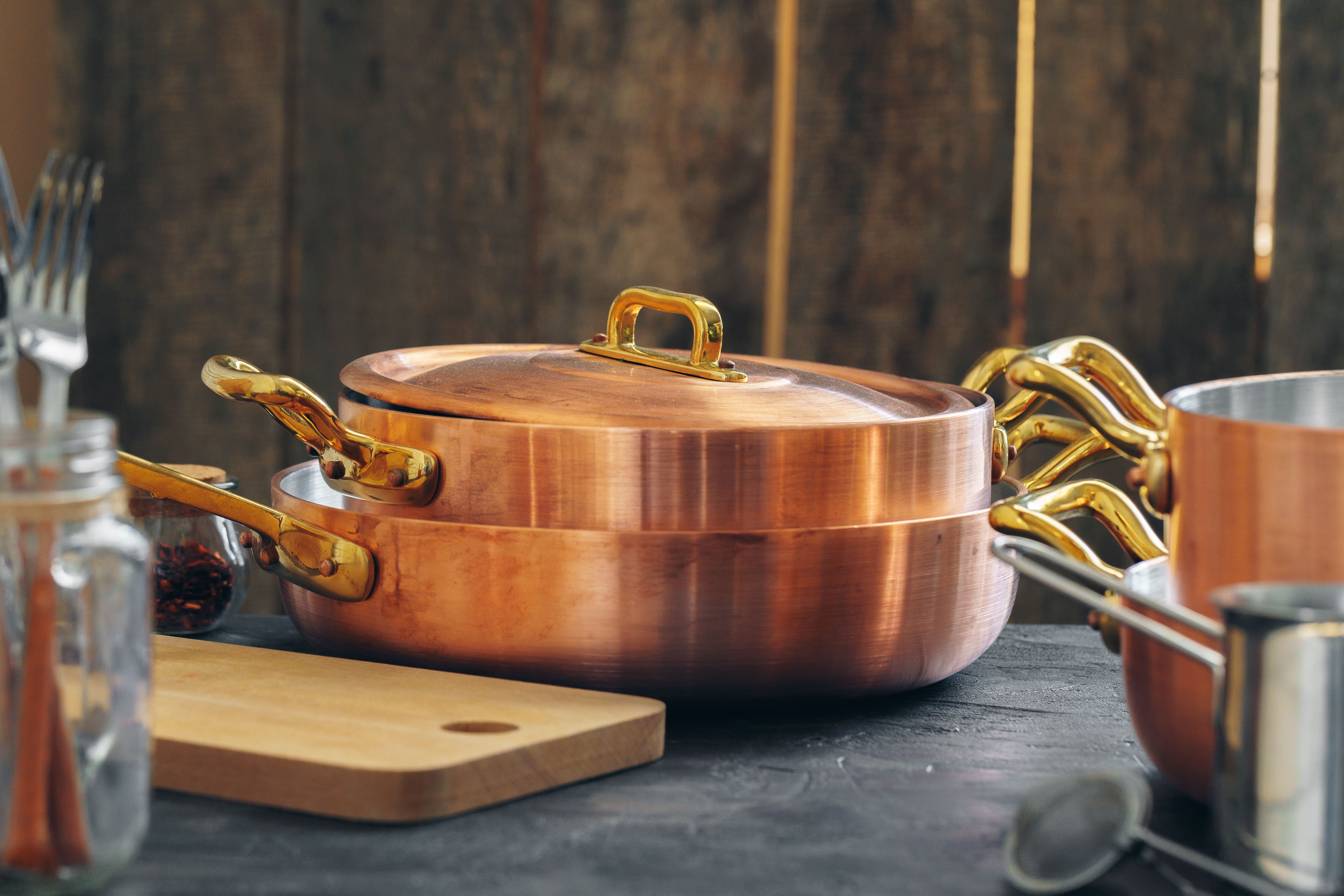 Copper cookware set sitting beside a cutting board and other kitchen utensils